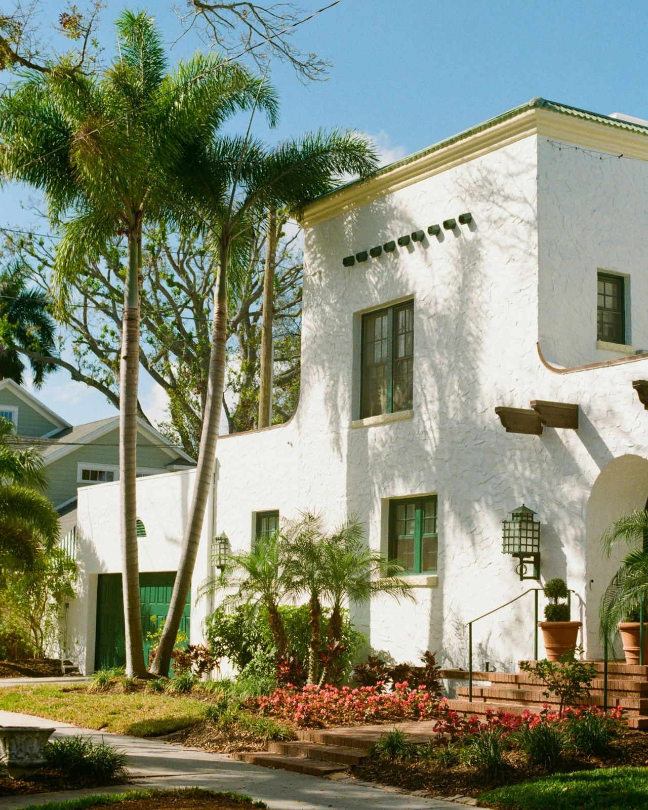 White stucco Florida home under tall palm trees before a storm